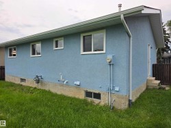 Blue stucco exterior with white-framed windows, white soffits, and white gutters - 