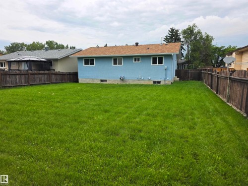 Expansive grassy yard with wood fencing and a light blue exterior - 1907 145A Avenue Nw, Edmonton, AB - Outdoor With Backyard With Exterior
