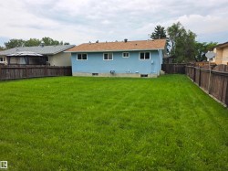 Expansive grassy yard with wood fencing and a light blue exterior - 