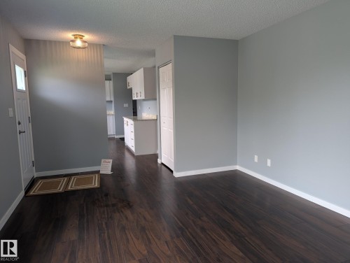 Dark wood-finish flooring, light grey painted walls, white trim, and a white paneled door - 1907 145A Avenue Nw, Edmonton, AB - Indoor Photo Showing Other Room