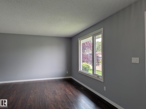 Wood-finish flooring, light gray wall paint, white trim, and a window with white casing - 1907 145A Avenue Nw, Edmonton, AB - Indoor Photo Showing Other Room