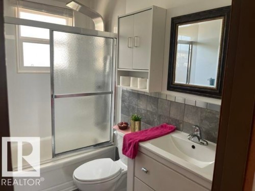 Bathroom featuring a white vanity with integrated sink, chrome faucet, and tiled backsplash - 5213 50 Avenue, Vegreville, AB - Indoor Photo Showing Bathroom