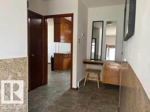 Entry featuring tiled flooring, wainscoting, and a built-in desk with mirrors - 5213 50 Avenue, Vegreville, AB - Indoor Photo Showing Other Room