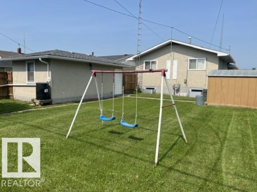 Expansive green lawn with a storage shed and a full-size swing set - 5213 50 Avenue, Vegreville, AB - Outdoor