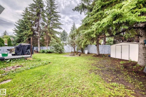Expansive backyard with a manicured lawn, mature trees, a built-in fire pit, and a storage shed - 6 Atkinson Place, St. Albert, AB - Outdoor