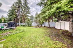 Expansive backyard with a manicured lawn, mature trees, a built-in fire pit, and a storage shed - 