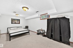 Spacious basement room featuring carpeted flooring, recessed ceiling lighting, and a wood-frame bed frame - 