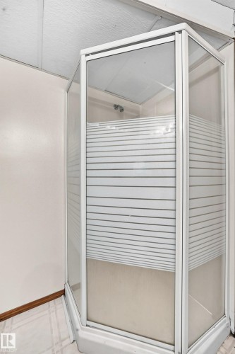 Corner shower enclosure with white framing, frosted glass panels, and a white shower base - 6 Atkinson Place, St. Albert, AB - Indoor