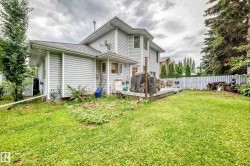 Exterior featuring light-colored horizontal siding, a multi-level deck, a fenced yard, and mature trees - 