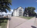 Multi-story building featuring multiple balconies, sloped roofs, and an asphalt driveway - #208 6710 158 Av Nw, Edmonton, AB  - Outdoor With Balcony 