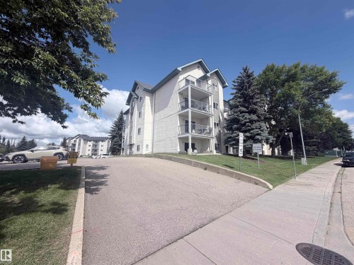Multi-story building featuring multiple balconies, sloped roofs, and an asphalt driveway - #208 6710 158 Av Nw, Edmonton, AB - Outdoor With Balcony