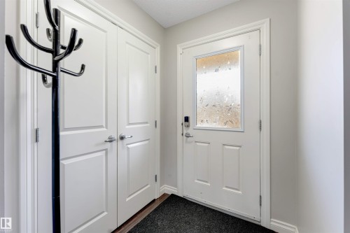 Entryway featuring a white door with a decorative glass insert, a digital lock, and a double-door closet with panel detailing - 3106 15 Avenue Nw, Edmonton, AB - Indoor Photo Showing Other Room