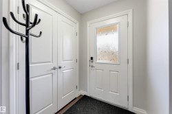Entryway featuring a white door with a decorative glass insert, a digital lock, and a double-door closet with panel detailing - 