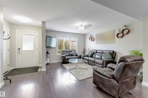 Entryway with a white door featuring a frosted glass insert, opening into a living area with wood-finish flooring - 3106 15 Avenue Nw, Edmonton, AB - Indoor Photo Showing Living Room