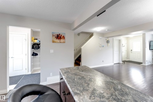 Kitchen island with stone-finish countertop, dark wood-finish cabinetry, and dark wood-finish flooring - 3106 15 Avenue Nw, Edmonton, AB - Indoor