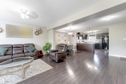 Spacious living area with wood-finish flooring, recessed lighting, and a ceiling fan - 