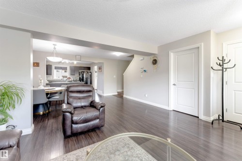 Wood-finish flooring throughout, white interior doors, and a staircase with a white railing - 3106 15 Avenue Nw, Edmonton, AB - Indoor Photo Showing Living Room