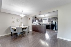 Wood-finish flooring throughout, integrated kitchen island, dark wood-finish cabinetry, built-in appliances, and recessed lighting - 
