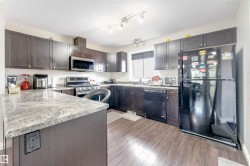 Kitchen featuring wood-finish flooring, dark wood cabinetry, light-toned countertops, and a full suite of black and stainless steel appliances - 