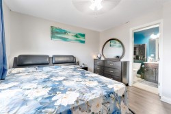 Wood-finish flooring, ceiling fan, and an ensuite bathroom featuring a vanity with an integrated sink - 