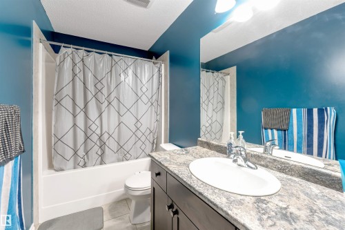 Bathroom featuring a built-in tub and shower combination, vanity with an integrated sink, patterned countertop, and dark wood-finish cabinetry - 3106 15 Avenue Nw, Edmonton, AB - Indoor Photo Showing Bathroom