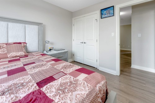 Upholstered headboard, double-door closet, light wood-finish flooring, and painted walls - 3106 15 Avenue Nw, Edmonton, AB - Indoor Photo Showing Bedroom