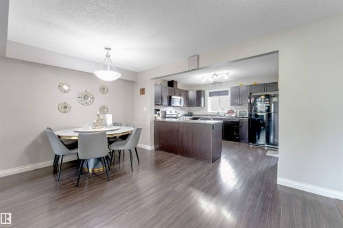 Wood-finish flooring throughout, integrated kitchen island, dark wood-finish cabinetry, built-in appliances, and recessed lighting - 3106 15 Avenue Nw, Edmonton, AB - Indoor