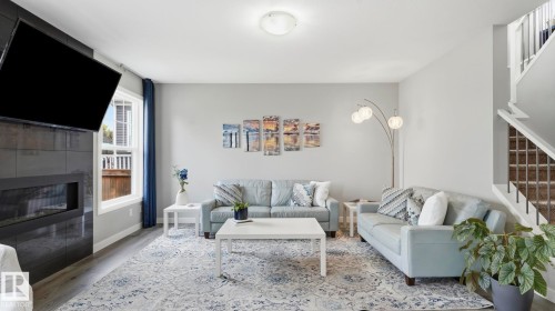 Bright, open living area featuring a gas fireplace with black surround, recessed ceiling lighting, and large windows with natural light - 63 Rosemount Boulevard, Beaumont, AB - Indoor Photo Showing Living Room With Fireplace