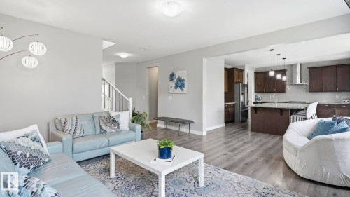 Open-concept living space featuring a light gray color palette, wood-finish flooring throughout, and abundant natural light from recessed ceiling fixtures - 63 Rosemount Boulevard, Beaumont, AB - Indoor Photo Showing Living Room
