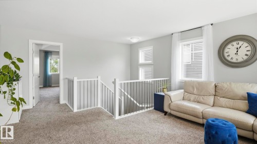 Carpeted landing with white railing staircase, multiple windows, and light gray walls - 63 Rosemount Boulevard, Beaumont, AB - Indoor Photo Showing Living Room