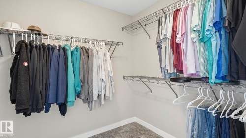 Walk-in closet featuring wire shelving, hanging rods, and carpet flooring - 63 Rosemount Boulevard, Beaumont, AB - Indoor With Storage