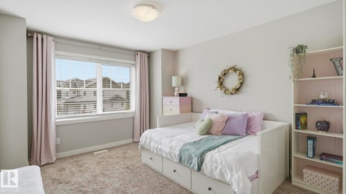 Bright secondary bedroom featuring large multi-pane windows with plantation shutters, built-in storage bed with drawers, and open shelving cabinetry - 63 Rosemount Boulevard, Beaumont, AB - Indoor Photo Showing Bedroom