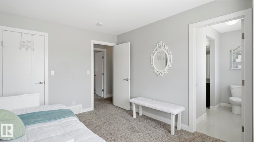 Primary Bedroom Suite with Multiple Access Points and En-Suite Bathroom  Spacious bedroom featuring neutral gray walls, carpeted flooring, and abundant natural light from recessed ceiling fixtures - 63 Rosemount Boulevard, Beaumont, AB - Indoor Photo Showing Bedroom