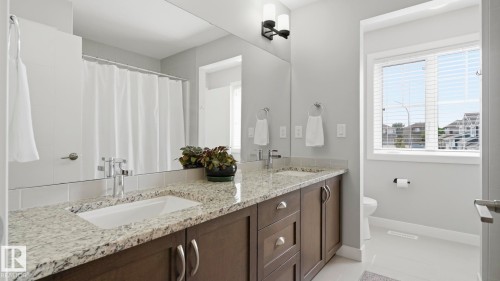 Spa-inspired primary bathroom featuring a dual-sink vanity with stone countertops, dark wood cabinetry, and polished chrome hardware - 63 Rosemount Boulevard, Beaumont, AB - Indoor Photo Showing Bathroom