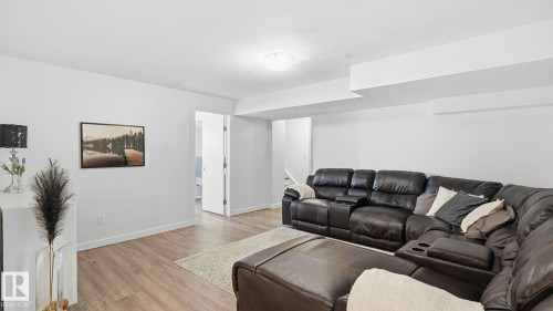 Spacious basement recreation room featuring wood-finish flooring, recessed ceiling lighting, and a large sectional seating area - 63 Rosemount Boulevard, Beaumont, AB - Indoor Photo Showing Living Room