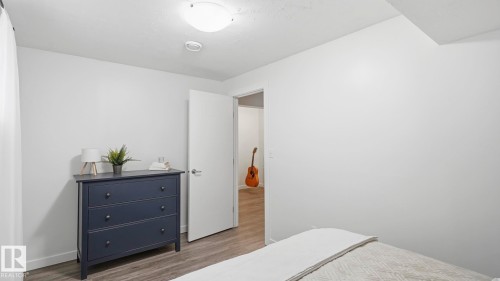 Bright secondary bedroom showcasing white walls, wood-finish flooring, and ample natural lighting - 63 Rosemount Boulevard, Beaumont, AB - Indoor Photo Showing Bedroom