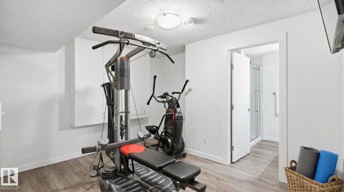 Dedicated fitness room featuring wood-finish flooring, recessed ceiling lighting, and ample space for exercise equipment - 63 Rosemount Boulevard, Beaumont, AB - Indoor Photo Showing Gym Room