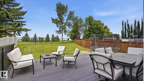 Expansive composite deck featuring multiple seating zones with integrated dining and lounge areas, overlooking manicured grounds and mature landscaping - 63 Rosemount Boulevard, Beaumont, AB - Outdoor With Deck Patio Veranda