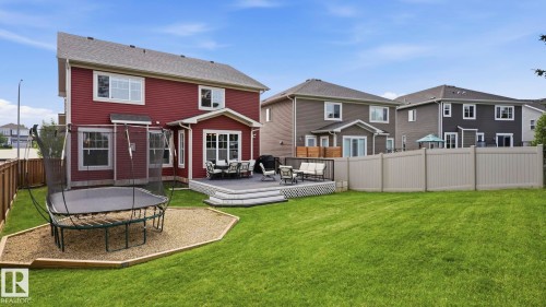 Expansive backyard oasis featuring a manicured lawn, circular paver patio with integrated seating area, composite deck with dining space, and vinyl privacy fencing - 63 Rosemount Boulevard, Beaumont, AB - Outdoor With Exterior