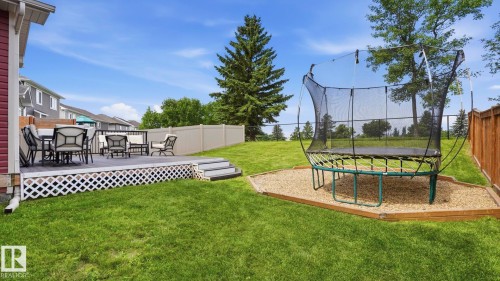 Spacious backyard featuring a multi-level deck with lattice skirting, expansive lawn, and a light-toned privacy fence - 63 Rosemount Boulevard, Beaumont, AB - Outdoor With Deck Patio Veranda