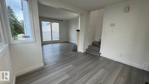 Light wood-finish flooring throughout, bright white walls, and a sliding glass door - 41 Lancaster Terrace Nw, Edmonton, AB - Indoor Photo Showing Other Room