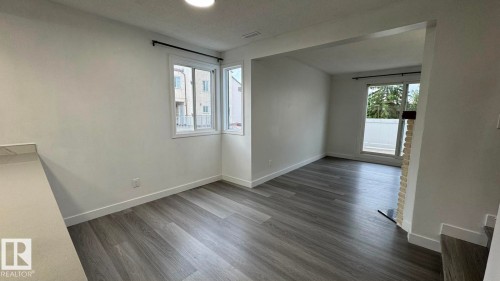 Expansive room featuring wood-finish flooring, white walls, and a large window with a black curtain rod - 41 Lancaster Terrace Nw, Edmonton, AB - Indoor Photo Showing Other Room