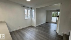 Expansive room featuring wood-finish flooring, white walls, and a large window with a black curtain rod - 