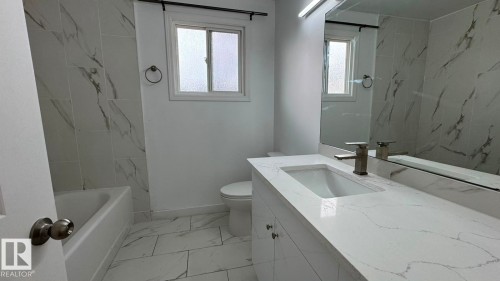 Bathroom featuring a built-in vanity with an integrated sink, a large mirror, and a modern faucet - 41 Lancaster Terrace Nw, Edmonton, AB - Indoor Photo Showing Bathroom