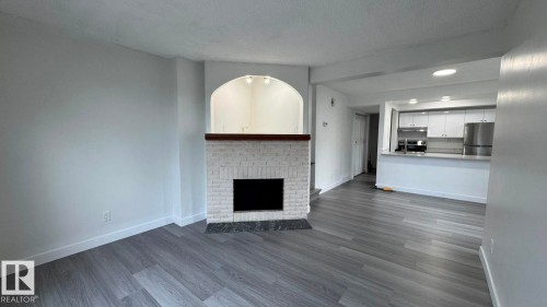 Recessed lighting, wood-finish flooring, white brick fireplace, wood mantel, stainless steel refrigerator - 41 Lancaster Terrace Nw, Edmonton, AB - Indoor Photo Showing Other Room With Fireplace
