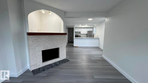 White brick fireplace with dark stone hearth, wood-finish mantel, and arched opening - 41 Lancaster Terrace Nw, Edmonton, AB - Indoor With Fireplace