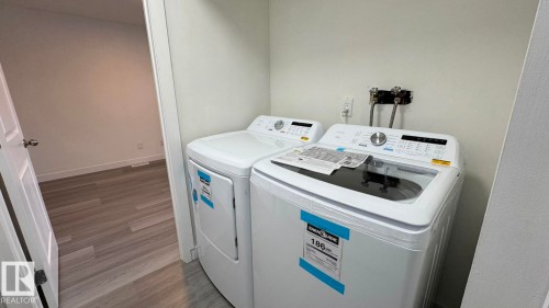Utility area with washer and dryer, adjacent to a room with wood-finish flooring - 41 Lancaster Terrace Nw, Edmonton, AB - Indoor Photo Showing Laundry Room