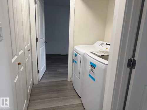 Integrated laundry area with white appliances, wood-finish flooring, and bi-fold closet doors - 41 Lancaster Terrace Nw, Edmonton, AB - Indoor