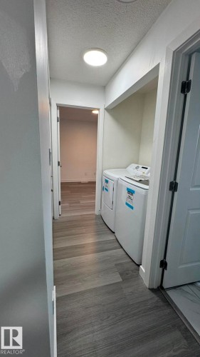 Hallway laundry area featuring a built-in recessed alcove, wood-finish flooring, and a circular ceiling light fixture - 41 Lancaster Terrace Nw, Edmonton, AB - Indoor Photo Showing Laundry Room