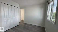 Wood-finish flooring, white walls, and a large window providing ample natural light - 